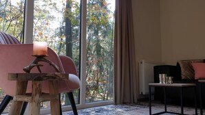 Una stanza con un'ampia finestra, una sedia di legno, un tavolino e un divano.