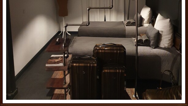 Un dormitorio con una cama, un maniquí, una maleta y una lámpara.
