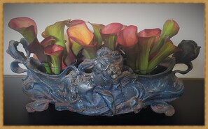 A decorative metal vase with calla lilies and a sculpted figure. - Kolev Apartments (Kelsterbach)