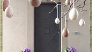 Una puerta decorada con huevos colgantes y dos macetas a cada lado.