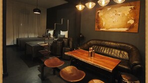 Un interior moderno con zona de comedor que incluye una mesa de madera y asientos de cuero, un cuadro abstracto grande en la pared e iluminación colgante.