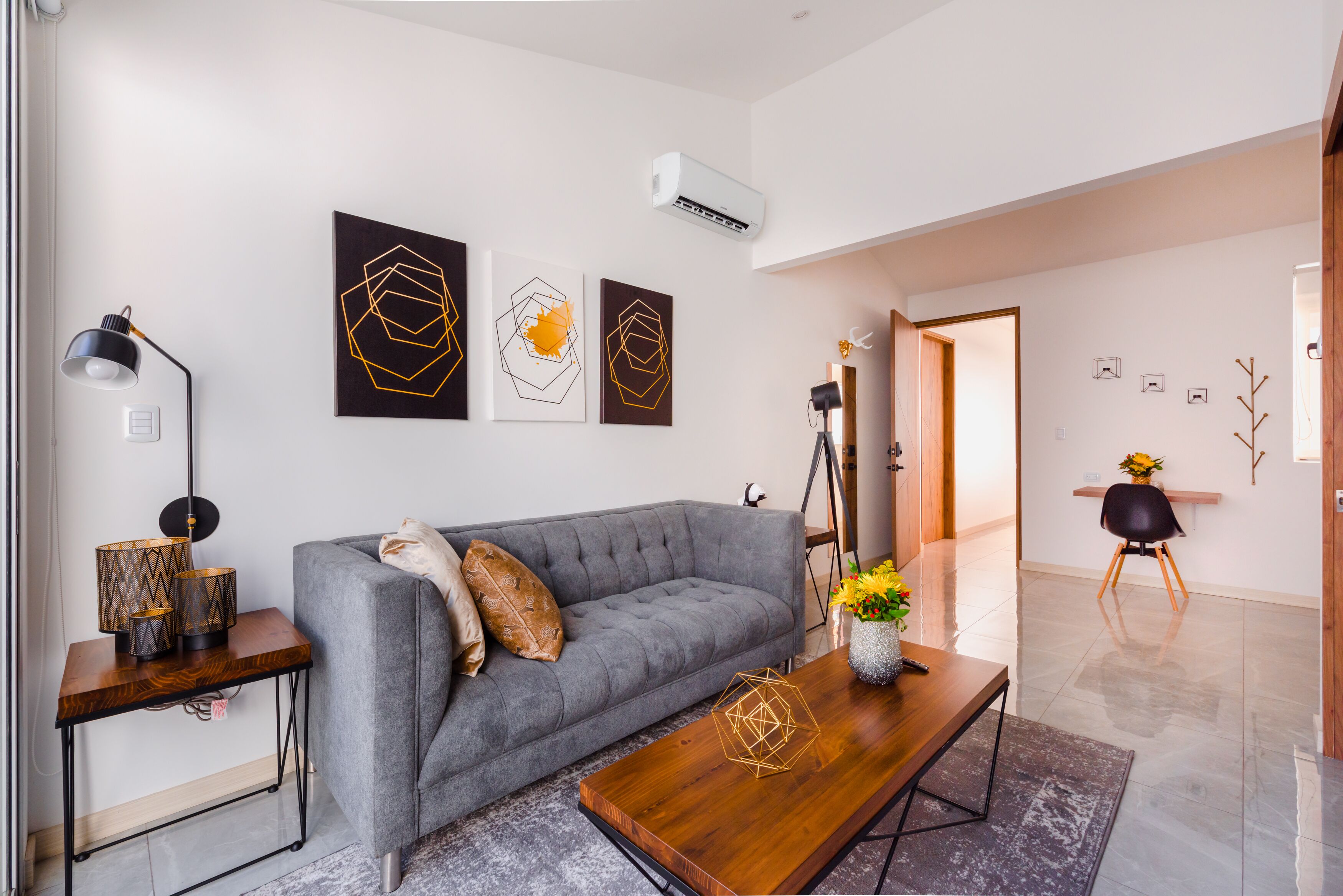 A modern living room with a grey sofa, a wooden coffee table, and abstract wall art.