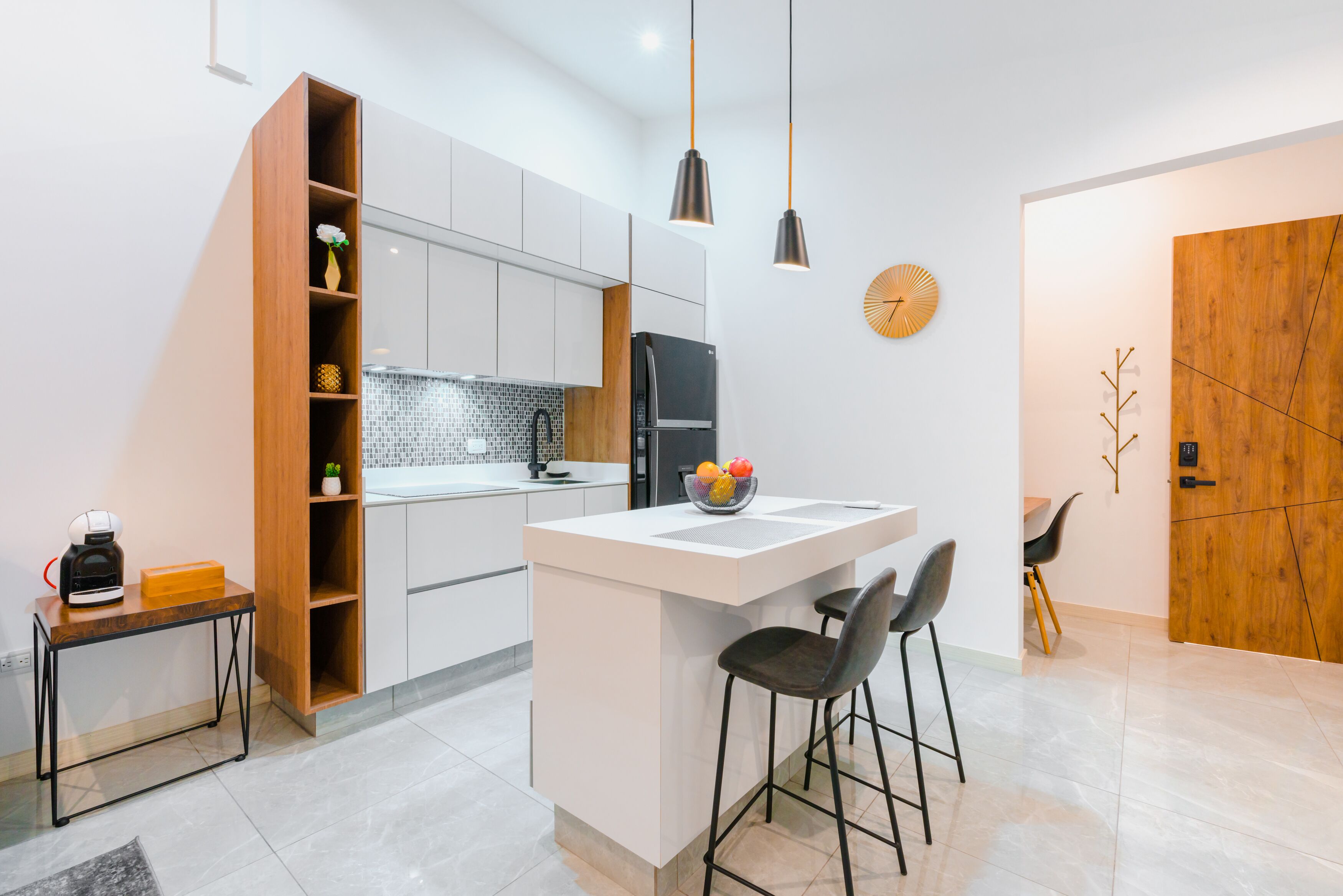 A modern kitchen with a central island, a coffee machine, and a wooden cabinet.