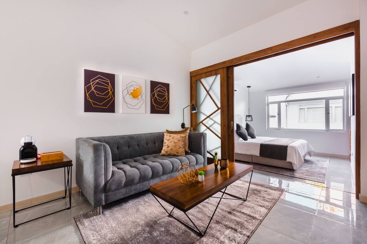 A modern living room with a grey sofa, a wooden coffee table, and a large window.
