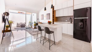 A modern kitchen with a black refrigerator, white cabinets, and a large island with bar stools.