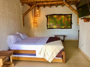A bedroom with a wooden bed, a bench, a wall-mounted light fixture, and a large abstract painting.
