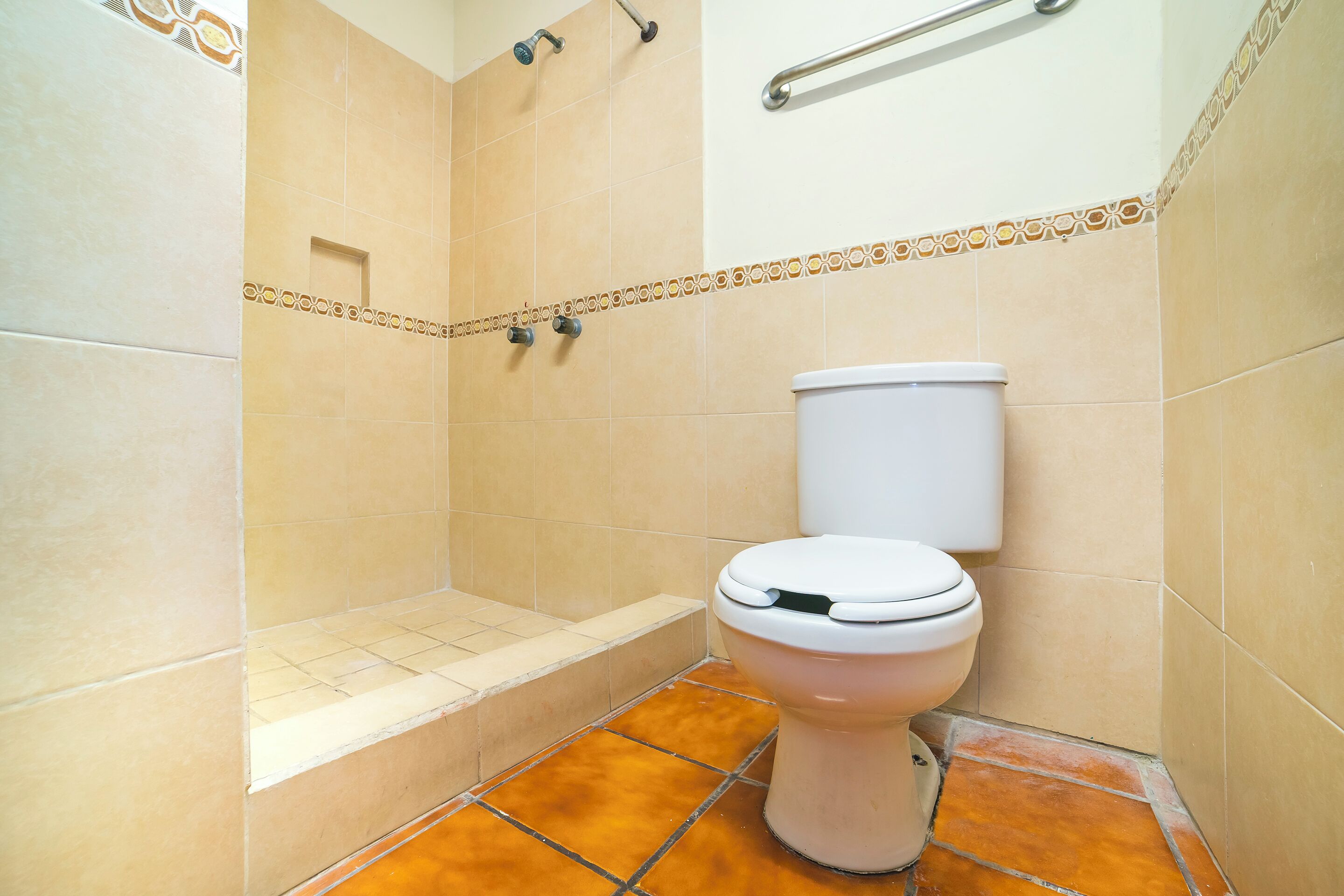 A bathroom with a toilet, shower, and tiled floor.