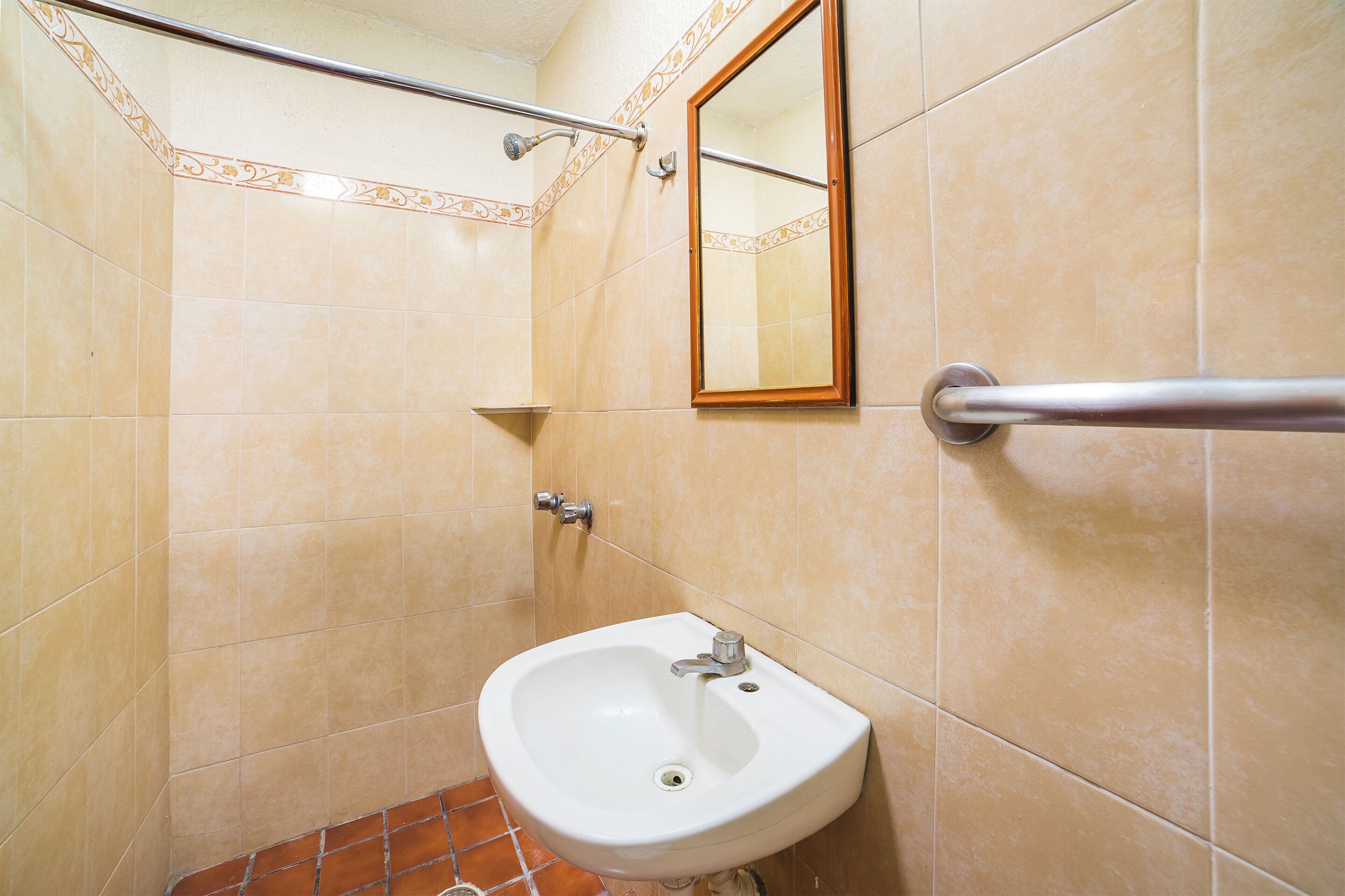 Un baño con lavabo, espejo y barra de apoyo.