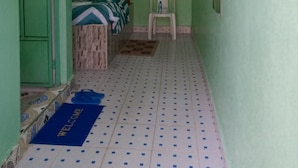 Un corridoio stretto con un letto, una sedia e un tappetino di benvenuto.