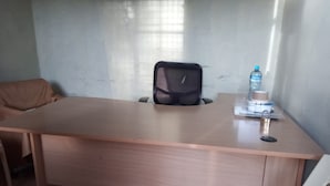 Un piccolo ufficio con una scrivania, una sedia e una bottiglia d'acqua sulla scrivania.