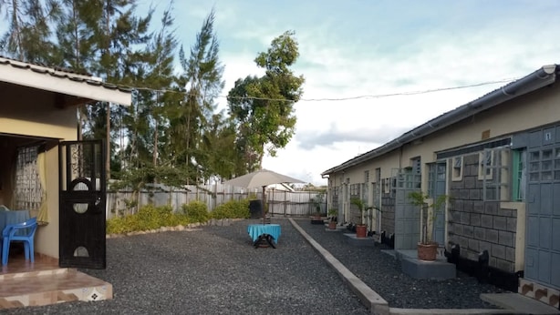 Un quartiere residenziale con vialetto sterrato, un tavolo blu e piante in vaso.