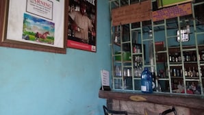 Un bar con manifesti appesi alle pareti, un bancone pieno di bottiglie e un cartello.