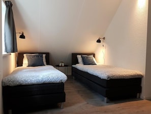A bedroom with two beds, each with a pillow and a small table between them.