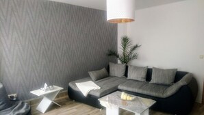 Ein modernes Wohnzimmer mit einem Ecksofa, einem Couchtisch und einem kleinen Beistelltisch.