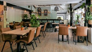 Ein Restaurant mit Holztischen und -stühlen, Zimmerpflanzen und einem modernen Interieur.