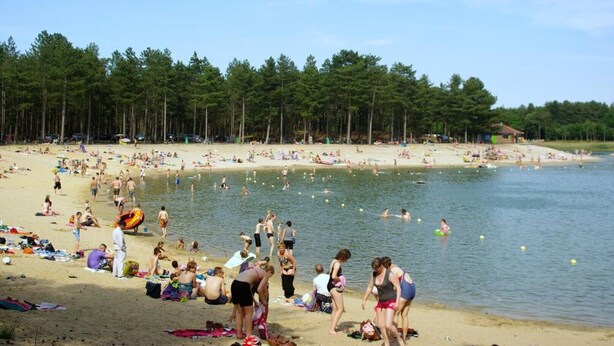 Ein Strand mit badenden und sonnenbächelnden Personen.