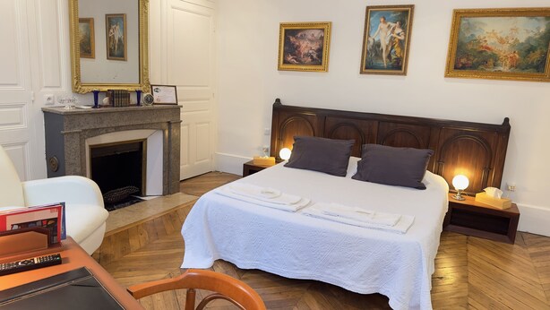 Una habitación de hotel con una cama grande, una chimenea y dos cuadros en la pared.
