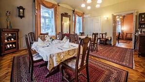 Comedor con una gran mesa dispuesta para seis personas, rodeada de sillas de madera, y un candelabro colgante.