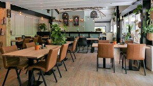 Un restaurant avec des tables et des chaises en bois, des plantes en pot et un décor intérieur moderne.