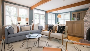 Ein Wohnzimmer mit einer Couch, Sesseln, einem Couchtisch und einem Kamin.