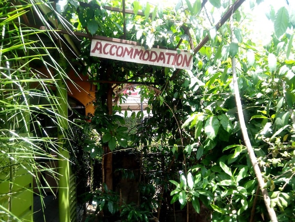 A sign labeled "ACCOMMODATION" amidst dense foliage, indicating a possible entrance to a building or garden area.