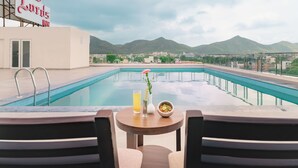 Vista a la piscina con una mesa, sillas y un cuenco de fruta.