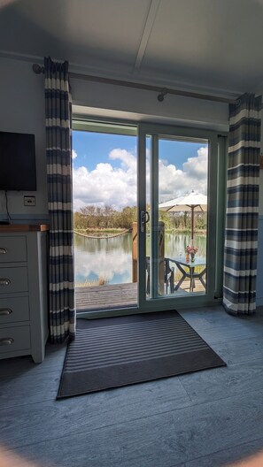Una habitación con puerta corrediza de vidrio que da a un patio junto al lago.