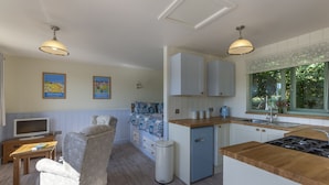 Cocina compacta con estufa integrada, un refrigerador pequeño y una ventana con vista a zonas verdes.