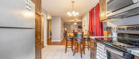 A modern kitchen with a refrigerator, stove, and dining area with chairs.