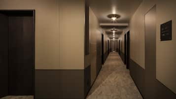 Um corredor comprido e estreito com piso coberto de carpete e portas em ambos os lados.