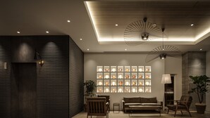 Un interior moderno con suelo de madera, un sofá, dos sillones, una mesa y una pared de luces esféricas iluminadas.
