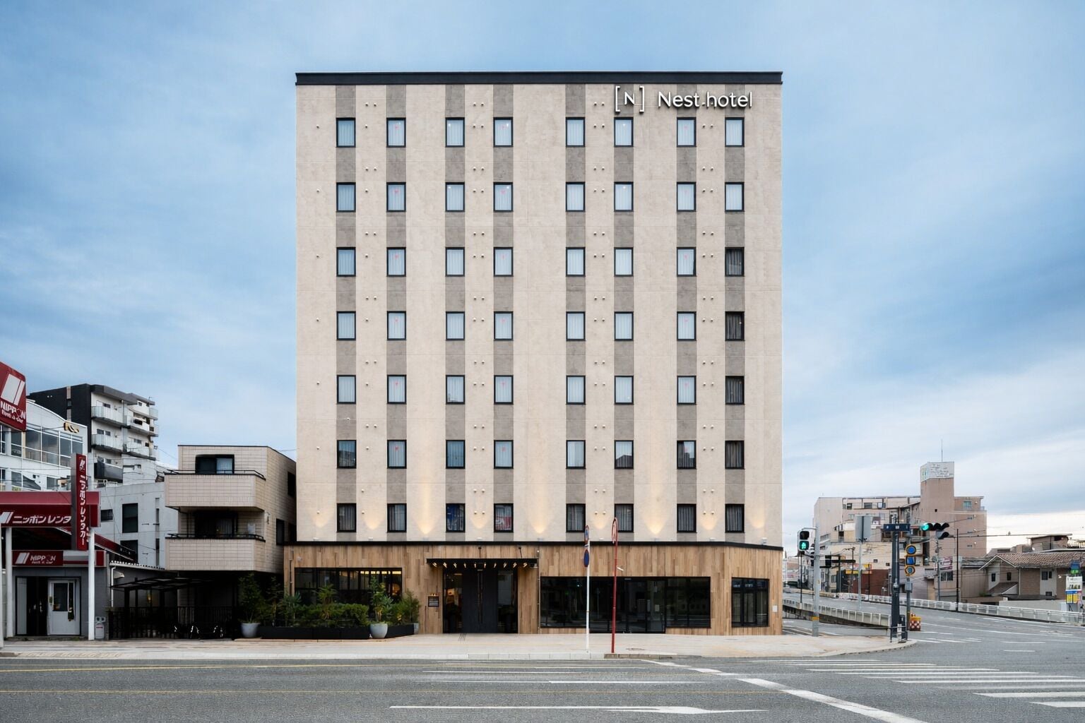 A tall, rectangular hotel with a modern facade, multiple windows, and a ground-level entrance.