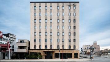 Un hotel alto y rectangular con fachada moderna, múltiples ventanas y acceso a nivel de calle.