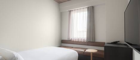 Una habitación de hotel moderna con cama, zona de estar y vistas a la ciudad, y un televisor de pantalla plana.