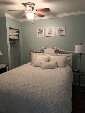 Ein Schlafzimmer mit einem Bett, einem Deckenventilator und drei Wandbildern.