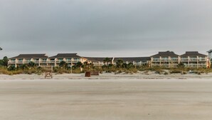 Un hôtel situé en bord de mer, composé de plusieurs bâtiments, avec une plage de sable et un poste de surveillance pour les sauveteurs.
