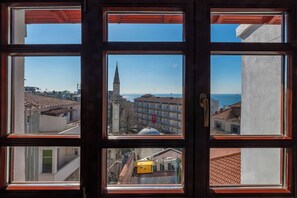 A view through a window with multiple panes, revealing a cityscape with buildings, a church spire, and a body of water. - Blue Gilroy Hotel (Istanbul)