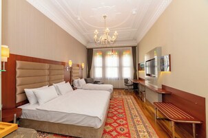 Una camera d'albergo con due letti, televisione, scrivania e lampadario.