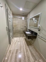 Un baño con cabina de ducha de vidrio, tocador con espejo y perchero para toallas.