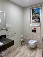 Un bagno con lavabo in marmo, water e uno specchio fissato alla parete.