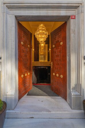 Une entrée imposante avec deux grandes portes en bois, un lustre et un panneau portant le chiffre « 8 ».