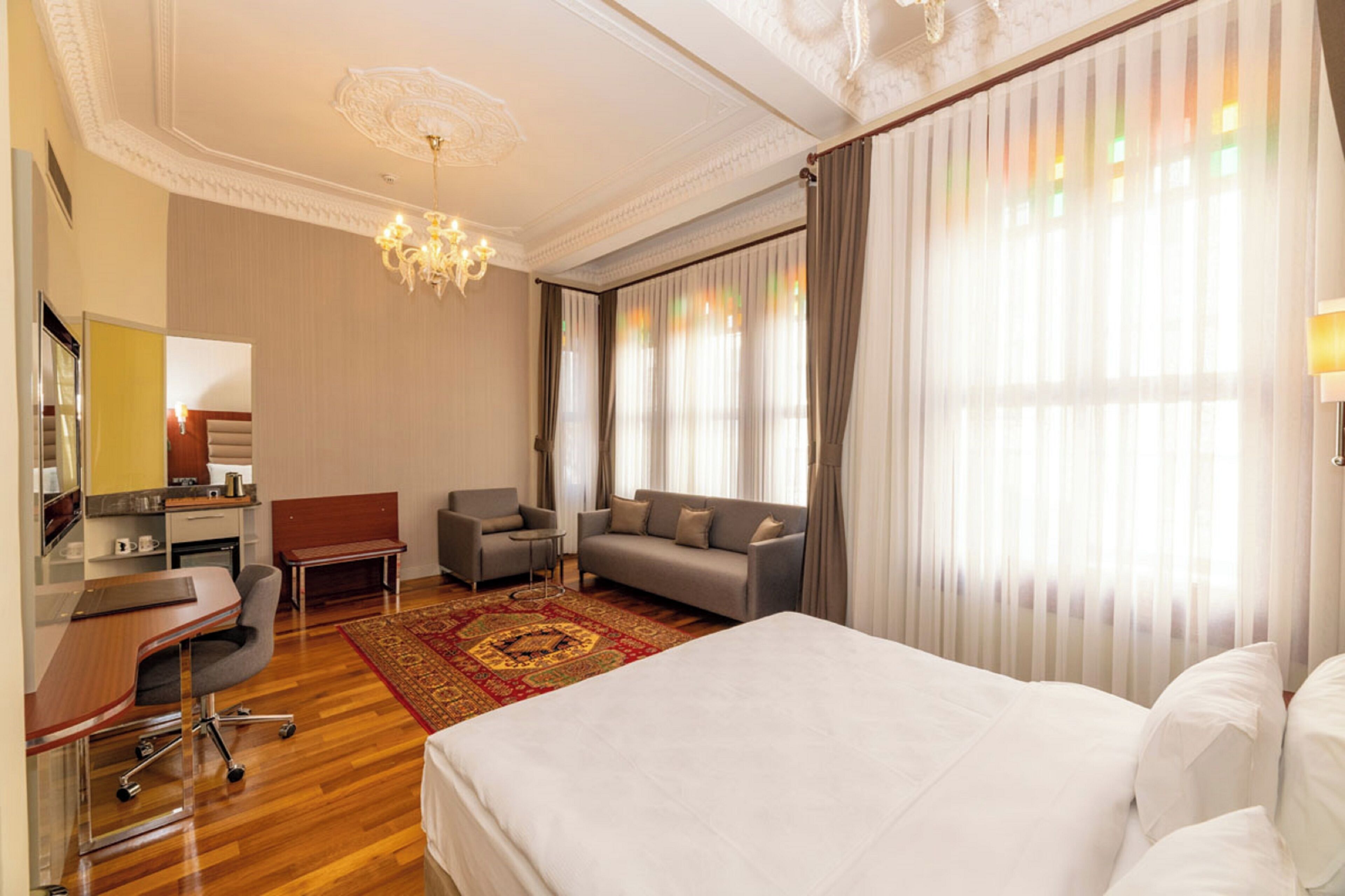 Una habitación de hotel con cama, escritorio, silla, sofá y candelabro.