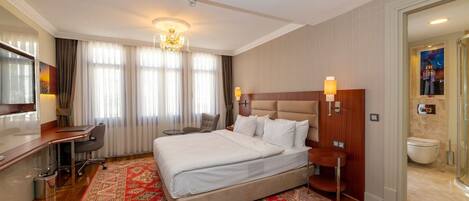 Hotelkamer met een groot bed, een bureau, een stoel, een televisie en een badkamer.