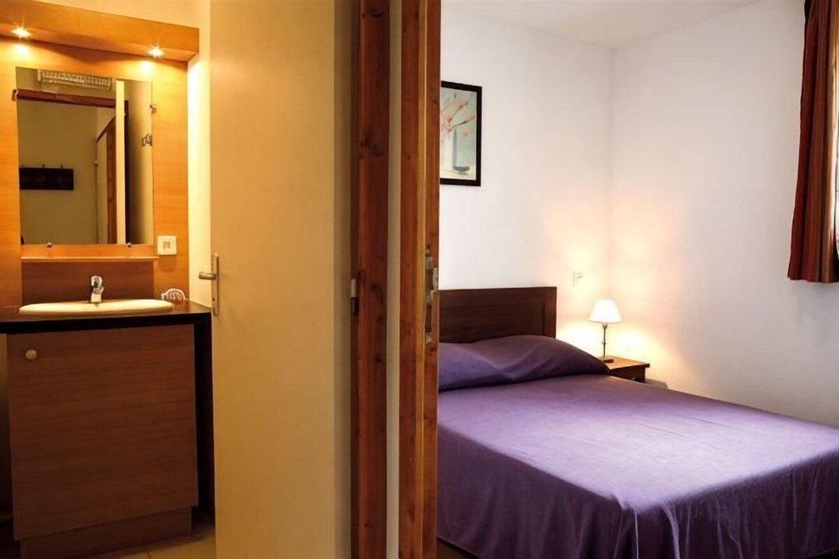 A bedroom with a wooden bed, a bedside table with a lamp, and a wooden dresser with a mirror.