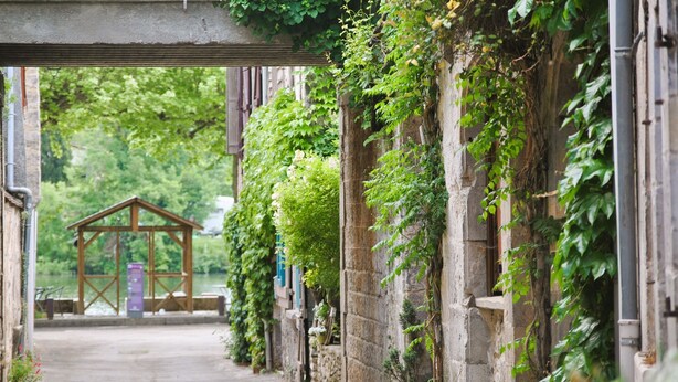 A narrow alleyway with stone walls covered in greenery, leading to a wooden structure in the distance. - Le Domaine des Cazelles by Ateya Vacances (Cajarc)