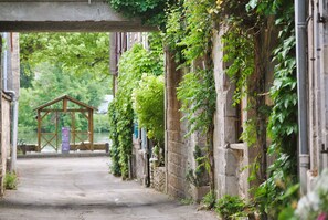A narrow alleyway with stone walls covered in greenery, leading to a wooden structure in the distance. - Le Domaine des Cazelles by Ateya Vacances (Cajarc)