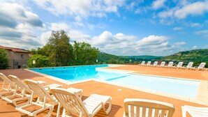 A swimming pool with lounge chairs and a view of hills. - Le Domaine des Cazelles by Ateya Vacances (Cajarc)