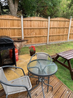 Une terrasse extérieure équipée d’un barbecue, de chaises et d’une table.