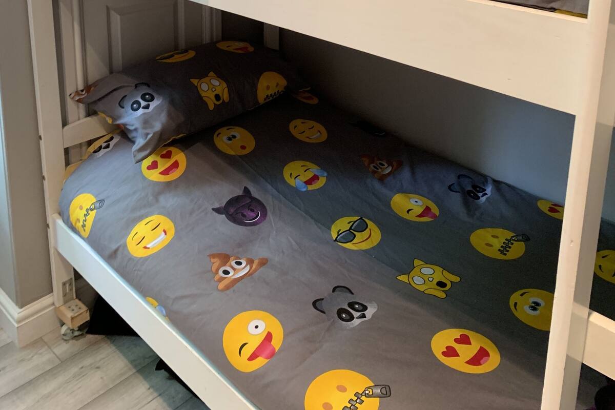 Ein Etagenbett mit grauem Lattenrost und verschiedenen Emoji-Motiven.
