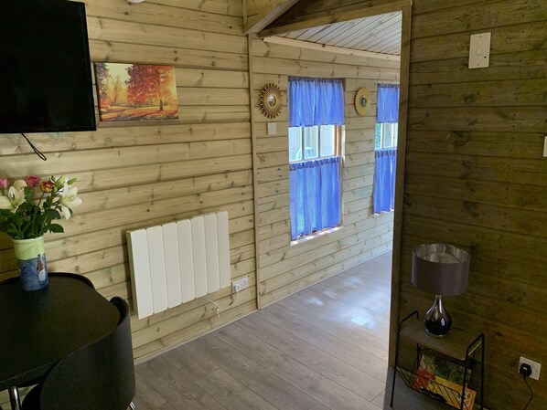 Een houten interieur met een televisie, een radiator en een raam met blauwe gordijnen.